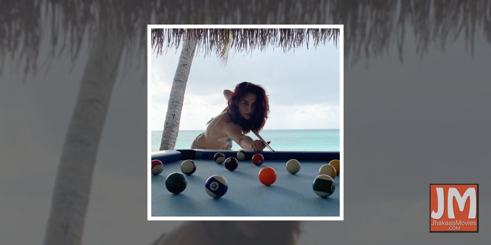 Elli AvrRam plays pool in bikini by the beach.