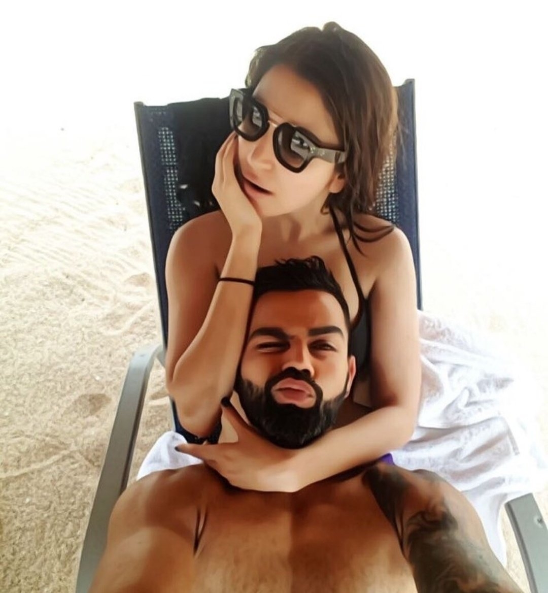 Virat Kohli posted a selfie on Instagram where he can be seen lying with his head on wife Anushkaâ€™s lap, who is sitting on a lounge chair on a sandy beach. In the selfie, which has the appearance of a watercolour painting due to a filter, Anushka flaunts a black bikini and shades. The actress seems to be staring at something while hubby Virat winks an eye looking at the camera and pouts for the selfie.